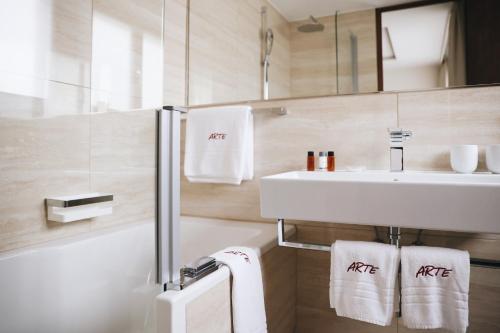 圣莫里茨阿尔特酒店的浴室配有盥洗盆、镜子和毛巾