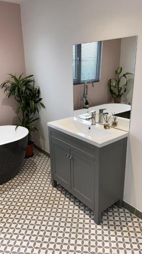 哈罗盖特Modern Harrogate house sleeps 10, cinema room & hot tub的一间带水槽、浴缸和镜子的浴室