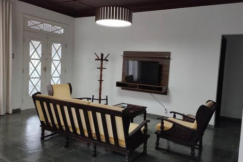乌巴图巴excelente casa ótima localização的客厅配有长椅、椅子和电视