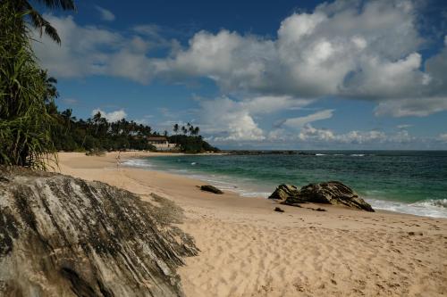 坦加拉MENAKA HOMESTAY的一片拥有岩石和海洋的沙滩