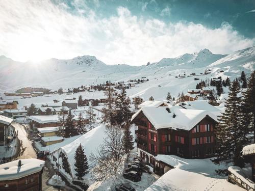 阿罗萨Hotel Garni Sonnenhalde的一座被雪覆盖的小镇,以群山为背景