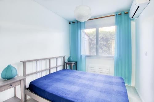 耶尔T3 L'Ecume Blanche - Jardin - Les Pesquiers- Clim Parking Plage à 100m BY HC的一间卧室设有蓝色的床和窗户。