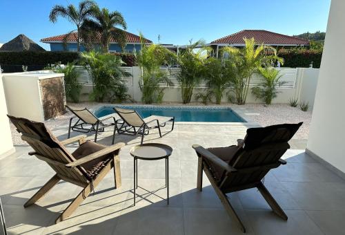 威廉斯塔德Villa Vista Montaña的一个带桌椅的庭院和一个游泳池