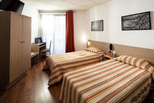 卢尔德Hôtel Hélianthe的酒店客房配有两张床和一张书桌
