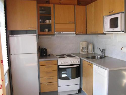 HattusaariKoli Country Club的小厨房配有白色家电和木制橱柜。