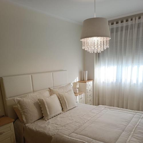 塞代拉Beiramar的卧室配有一张带吊灯的大型白色床。