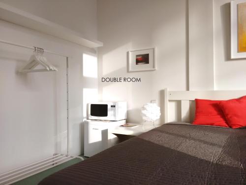 不莱梅洛夫特76号公寓的一间卧室配有一张带红色枕头的床和微波炉
