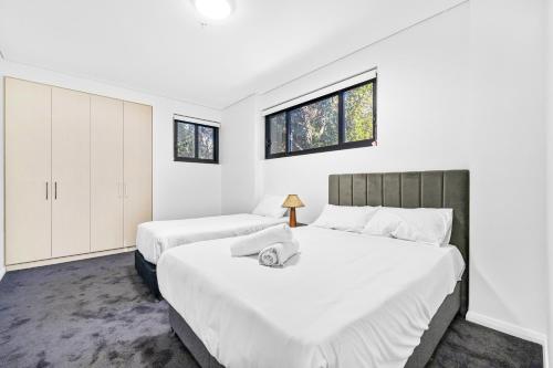 悉尼Urban Oasis in Heart of Homebush的卧室设有两张床,拥有白色的墙壁和窗户。