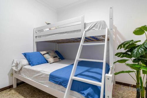 蓬塔翁布里亚Chalet a pie de playa的一张带蓝色枕头和梯子的白色双层床
