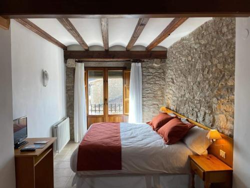 Ares del MaestreHotel D` Ares的一间卧室设有一张床和石墙