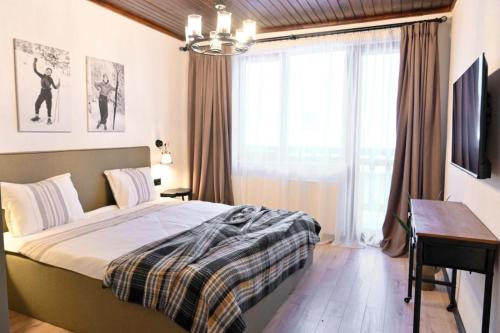 班斯科Marand Boutique Apartments的一间卧室配有一张床、一张书桌和一个窗户。