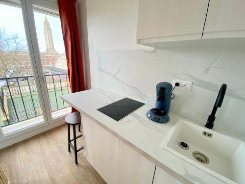 勒阿弗尔L'Escale Appartements et Suites en bord de Mer的带水槽的厨房和带艾菲尔铁塔的窗户