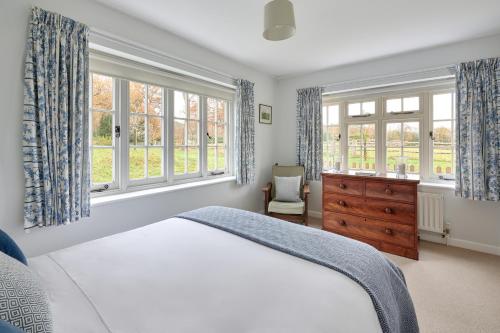 彼得斯菲尔德Garden flat near Goodwood with stunning views的一间卧室设有床、两个窗户和一个梳妆台