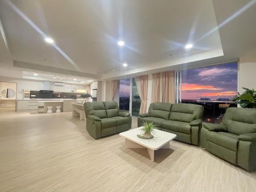 哥打京那巴鲁QUEENSLAND SUITES at Aru Suites, Kota Kinabalu的客厅配有两张绿色沙发和一张桌子