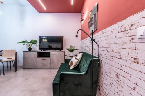 博洛尼亚Tartini Lofts的客厅设有绿沙发,靠砖墙