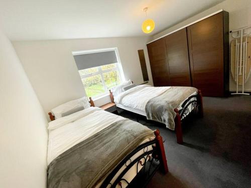 斯坦维尔Majestic Homes Heathrow - FREE PARKING的一间卧室设有两张床和窗户。