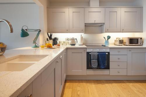 达特茅斯Harbour Living的白色的厨房配有白色橱柜和水槽