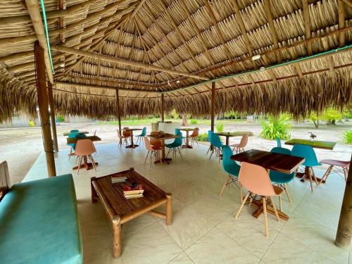 格兰德岛Hotel Las Casitas De Mar Adentro的一间设有桌子和椅子的稻草屋顶餐厅