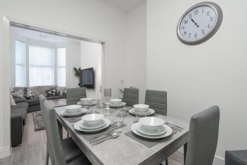 利物浦Hornsey Lodge - Anfield Apartments的一间设有桌子和墙上时钟的餐厅