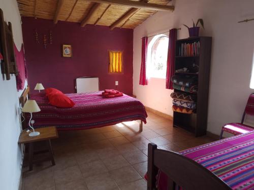 乌玛瓦卡Cabaña El Cardón,casita en el campo quebradeño的一间卧室配有一张带红色枕头的床