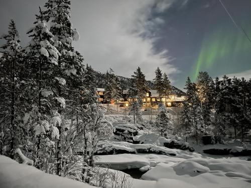 SkjåkPollfoss Hotell的雪中的房子,天空有彩虹