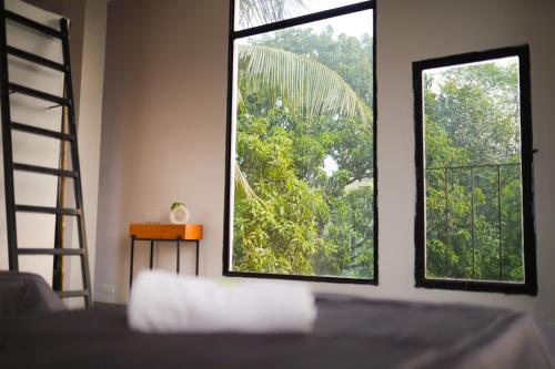 NavadwīpSoultoSoul Guesthouse的一间卧室配有床和两个树木窗户