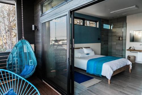 恩西尼塔斯Twelve Senses Retreat, a Member of Design Hotels的卧室设有秋千床和玻璃窗。