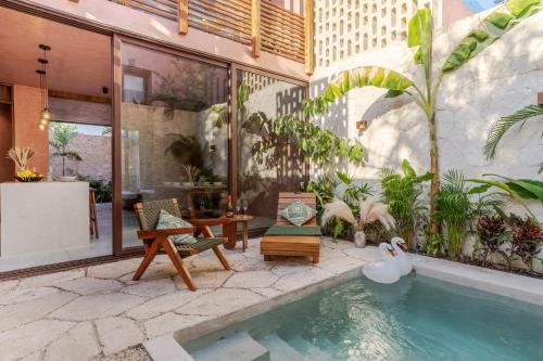 图卢姆Entorno Tulum - Luxury Villas的一座房子,设有一座带椅子和植物的游泳池