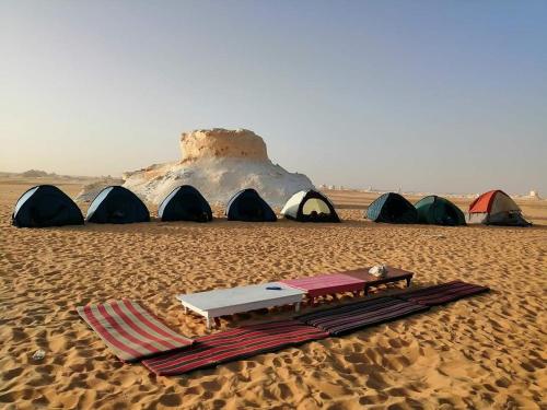 Qasr Al FarafirahWhite desert & Black desert camb的沙漠中一组帐篷,配有一张桌子和一张床垫