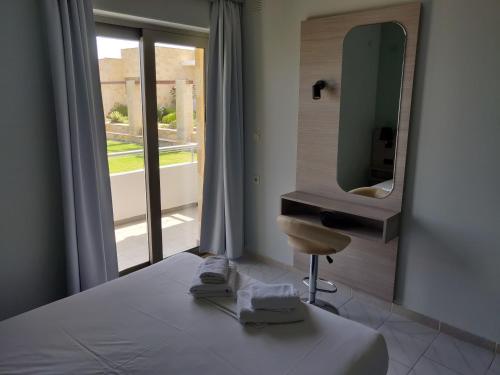 基萨莫斯维利亚海滩公寓酒店的一间卧室配有一张带镜子和椅子的床