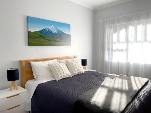 新普利茅斯Huatoki Hideaway Peaceful Central Location的卧室配有一张挂有山墙照片的床。