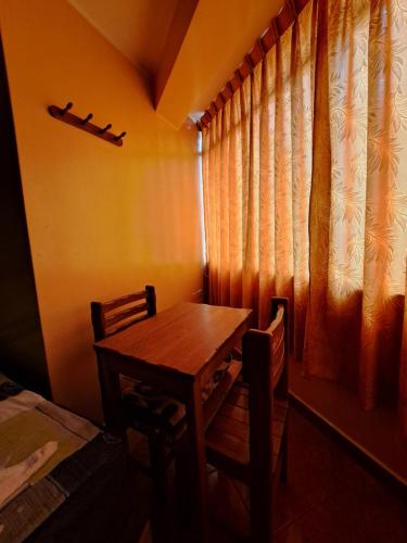 利马Hospedaje Leo的窗户客房内的一张木桌和椅子
