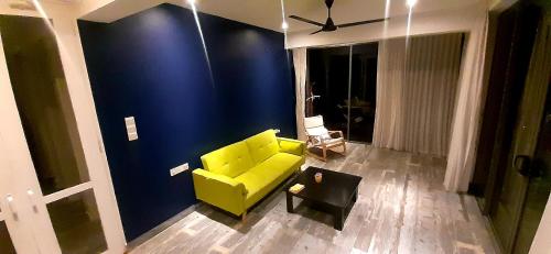 米瑞莎Marino Mirissa的客厅里设有一张黄色的沙发,客厅里设有蓝色的墙壁