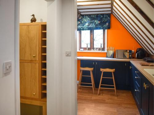 AshburnhamKingfisher Granary的厨房设有蓝色橱柜和橙色墙壁