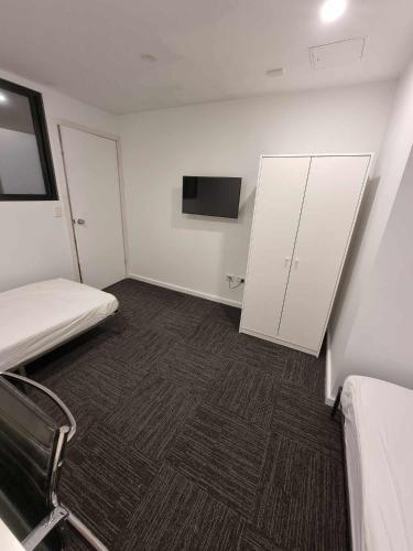 悉尼Sydney Airport Guest House的小房间设有床铺和电视