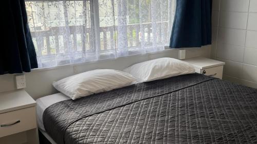 旺阿雷Aaron Court Motel Whangarei的一间卧室配有带两个枕头的床和窗户