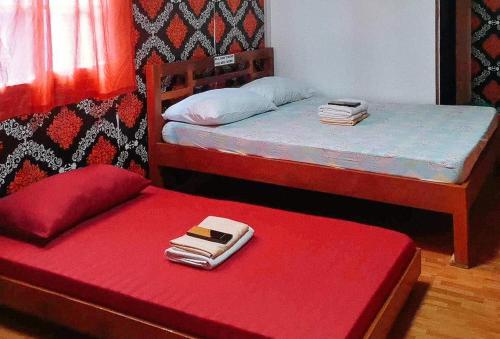 Dalumpinas OesteRedDoorz @ Boondocks Cabins Resort的一间卧室设有两张床和一张红色长凳及钱包