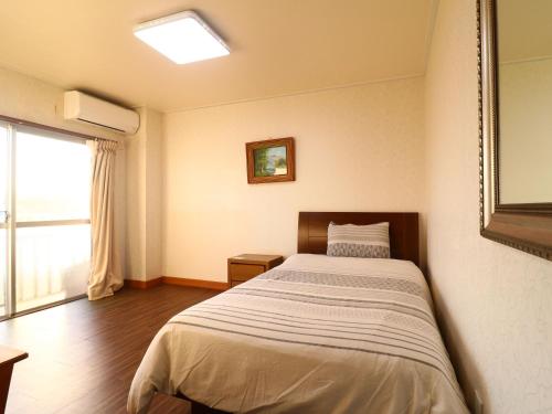 Katakaiゴールデンビーチホテル的一间带床的卧室,位于带窗户的房间内