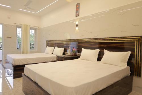 根尼亚古马里HOTEL CYRIL的配有白色床单的酒店客房内的两张床