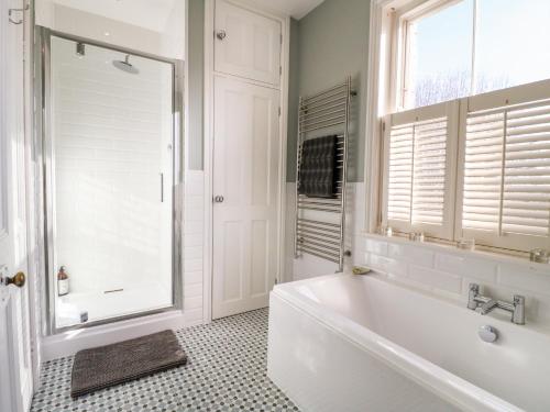 格兰瑟姆The Coach House的白色的浴室设有浴缸和窗户。