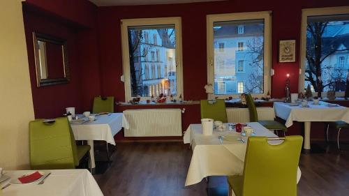 特里尔Ricks City Hotel的餐厅设有白色桌子和绿色椅子及窗户