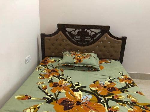 Pirojpur Guest House的一张带花卉棉被和两个枕头的床
