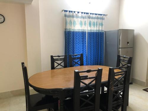 Pirojpur Guest House的餐桌、椅子和蓝色窗帘