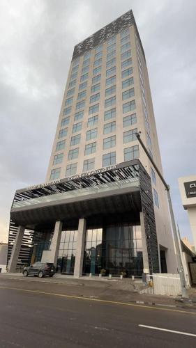 利雅德Msharef almoden hotel فندق مشارف المدن的一座高大的建筑,前面有一辆汽车