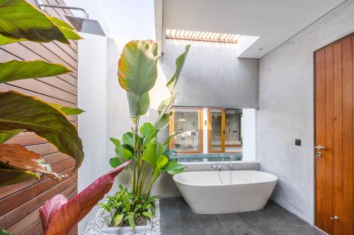 沙努尔J4 Villas Sanur的浴室配有白色浴缸和大植物