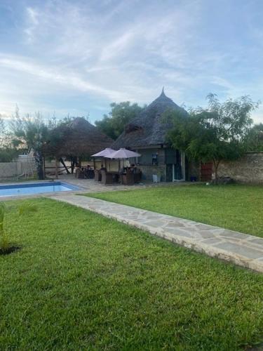 乌昆达Coral Villas Cottage的一座带草地庭院和游泳池的房子
