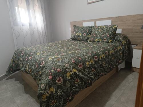 托莱多El bosque - CON PARKING GRATIS的一间卧室配有一张带花卉床罩的床