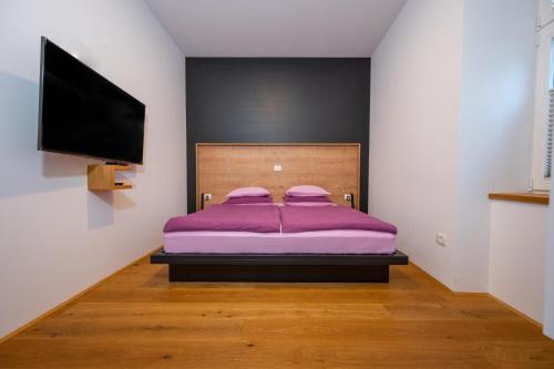 科切维Cirus apartments的一间卧室配有紫色的床和一台平面电视