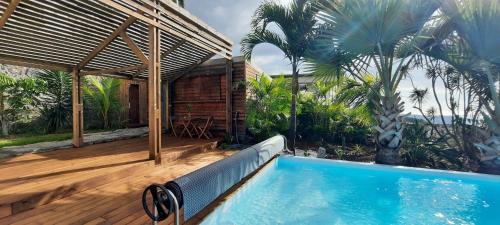 BellemèneBungalow cosy avec piscine surplombant l'océan的房屋旁的木甲板上的游泳池