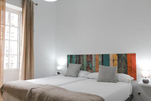 塞维利亚MonKeys Apartments Lumbreras Deluxe的一间卧室配有一张白色的床和色彩缤纷的床头板